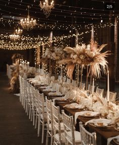 a long table is set with white chairs and tall centerpieces that have feathers on them