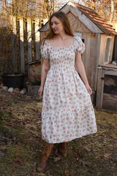 Gray Scroll Rose Bunches Floral Cotton Prairie Dress, Smocked Bodice, Puffed Sleeves, Midi Length, with Pockets Product Details: Embrace understated elegance with our Gray Scroll Rose Bunches Floral Cotton Prairie Dress. This sophisticated dress features a soft white backdrop adorned with delicate silver swirls and soft pink roses, creating a subtle yet enchanting pattern. The smocked bodice offers a comfortable, adjustable fit, while the puffed sleeves and flowy midi skirt enhance the classic prairie silhouette. Practical side pockets add a modern touch to this timeless design. Ideal for a variety of occasions, from casual gatherings to elegant events, this dress pairs beautifully with sandals or boots. Layer with a cardigan or jacket to transition seamlessly through the seasons. Key Feat Luxury Elegant Prairie Dress For Spring, Luxury Fitted Prairie Dress For Women, Luxury Elegant Prairie Dress, Luxury Fitted Romantic Prairie Dress, Luxury Fitted Elegant Prairie Dress, Prairie Dress Modern Casual, Soft Pink Roses, Sophisticated Dress, Prairie Dress