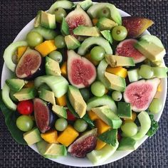 a white bowl filled with assorted fruits on top of a black tablecloth covered floor