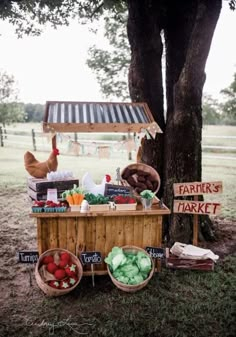 a farmer's market stand in the middle of a field next to a tree