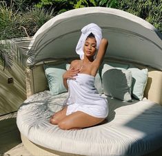 a woman sitting on top of a bed covered in a white bathrobe and towel