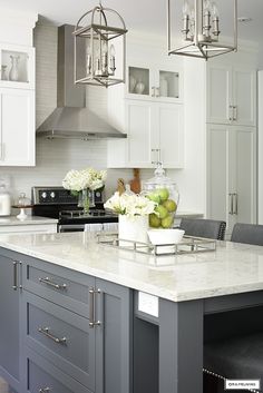 a large kitchen with white cabinets and marble counter tops, along with gray stools