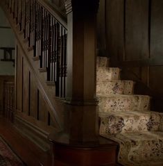 the stairs in this house are made of wood and have floral carpeting on them