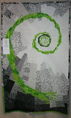 a green and white quilt hanging on a wall