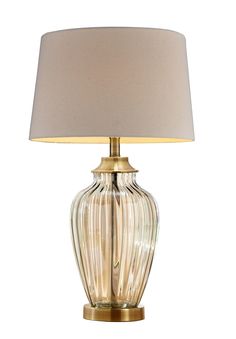 a glass table lamp with a beige shade on the base and a gold metal base