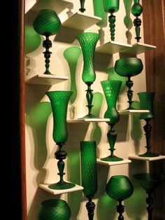 many green glass vases are displayed on shelves