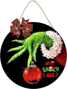 a christmas ornament hanging on a rope with a green grin face and red bauble