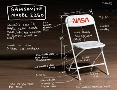 a white folding chair sitting on top of a wooden floor next to a blackboard