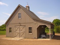 a large brown barn sitting on top of a dirt field