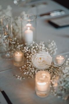 white flowers and candles on a table with silverware, napkins and place settings