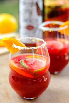 two glasses filled with drinks sitting on top of a table