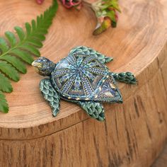 a small turtle figurine sitting on top of a wooden table next to a plant