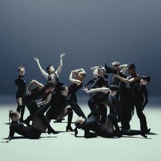 a group of people standing around each other in front of a dark background with their arms outstretched