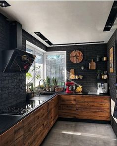 a kitchen with black brick walls and wooden cabinets is pictured in this image, there are plants on the counter