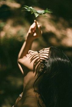 a woman is holding up a plant in the air with one hand and her other arm behind her head