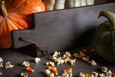 pumpkins, gourds and popcorn are scattered on a black surface next to a cutting board