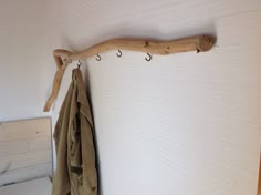 a coat rack made out of driftwood and hooks on the wall next to a bed