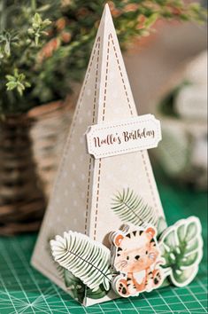 a small birthday card with a bear on it next to a potted plant in the background