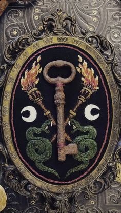 an ornate metal plaque with a key and two snakes on it's face, surrounded by other decorative items