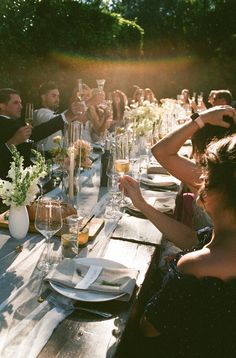 a group of people sitting at a long table with wine glasses on top of it