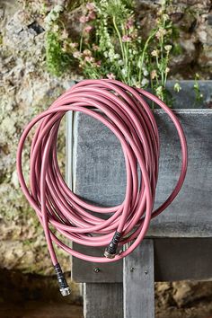 a bunch of pink cords sitting on top of a wooden table next to a flower pot