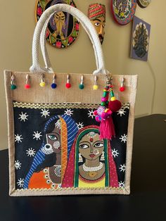 a handbag with an image of two women on the front and one is decorated with multicolored tassels