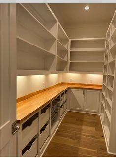 an empty kitchen with white cabinets and wood counter tops, along with drawers on both sides