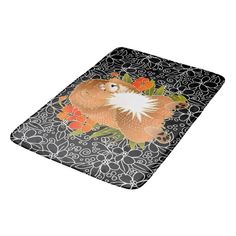 an orange and white cat sitting on top of a black flowered floor mat in front of a white background