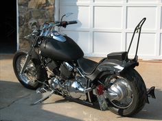 a black motorcycle parked in front of a garage