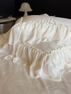 the bed is made with white ruffled sheets