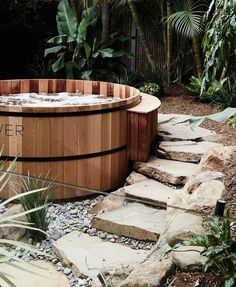 a wooden hot tub surrounded by plants and rocks in a garden area with the words river written on it