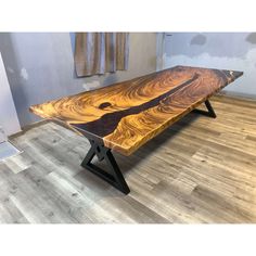 a wooden table sitting on top of a hard wood floor next to a window with curtains