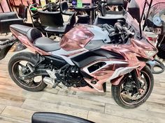 a pink motorcycle parked on top of a hard wood floor next to chairs and tables