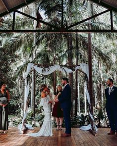 the bride and groom are getting married at their wedding ceremony in the forest with palm trees