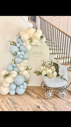 a baby carriage with balloons and flowers on the floor in front of a stair case