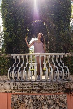 a woman standing on a balcony with her arms in the air