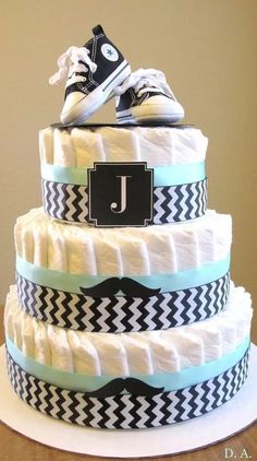 a three tiered diaper cake decorated with sneakers and a monogrammed ribbon