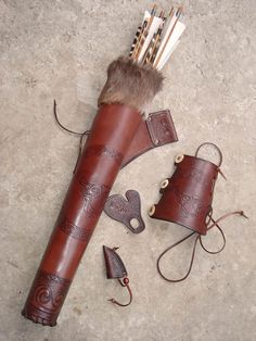 a leather case with some arrows and other items on the ground next to it,