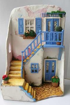 a doll house with blue shutters and steps leading up to the front door is shown