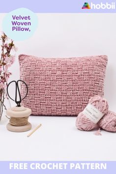 a crochet pillow, yarn and scissors on a table