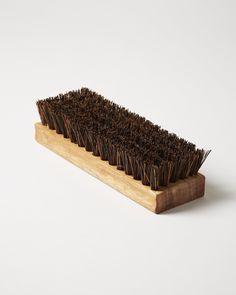 a wooden brush with brown bristles sitting on it's side against a white background