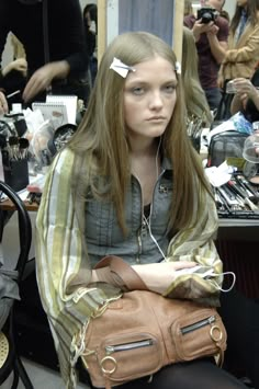 a mannequin is sitting in front of a mirror holding a brown handbag