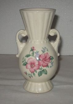 a white vase with pink flowers painted on it