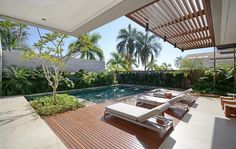 an outdoor swimming pool with lounge chairs and palm trees