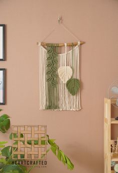 a wall hanging on the side of a pink wall next to a potted plant