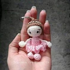 a small crocheted doll is held in someone's hand with a keychain