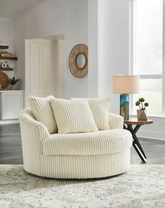 a living room filled with furniture and a round couch in front of a large window