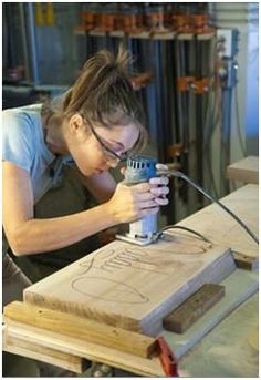 a woman working on a piece of wood with an electric grinder in her hands