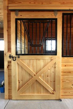 the inside of a horse barn with wooden walls and doors that have bars on them