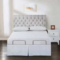 a white bed with two drawers and a headboard on top of it in a room